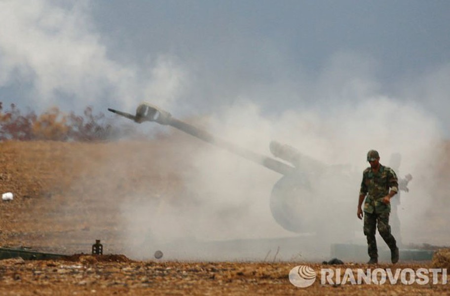 Trong những ngày đầu cuối tháng 10/2015,  quân đội  Syria đã giao tranh ác liệt IS nhằm mở đường tiếp cận thành phố Idlib. Ảnh: Một binh sỹ Syria đứng cạnh lựu pháo D30 122mm đang nhả khói mù mịt ở đầu nòng pháo.